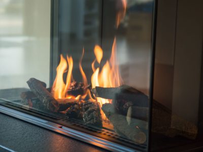 a fire burns in a glass fireplace, radiates heat