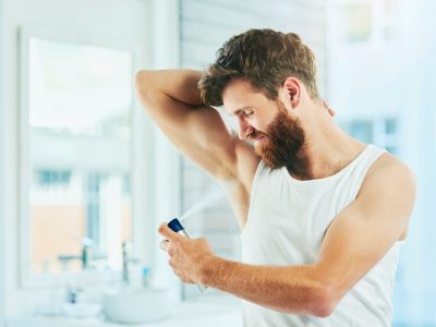 Cropped shot of a handsome young man spraying himself with deodorant