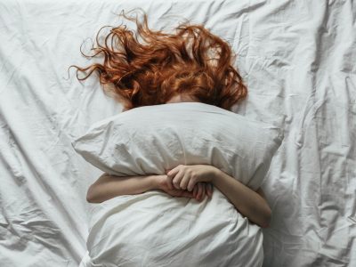 Red-haired little girl wakes up in the morning in her crib Red-haired little girl wakes up in the morning in her crib with white bed linen.