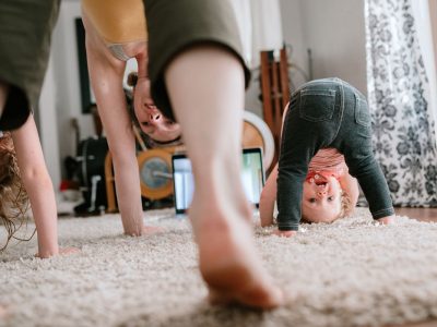 A mother does a virtual exercise class with her daughters in their living room.  Part of the regular routine or the new normal with social distancing and Covid-19.