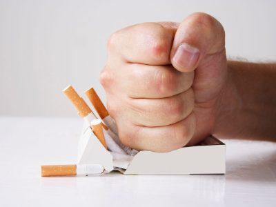 Hand crushing cigarettes over white background