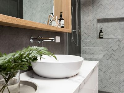 Bathroom details clean white basin with herringbone marble mosaic shower tiling behind