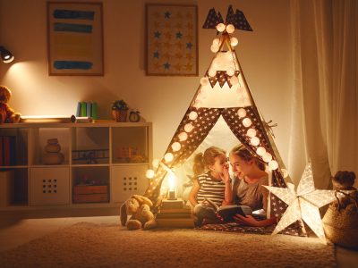 reading and family games in   tent. mother and child daughter with  book and flashlight before going to bed